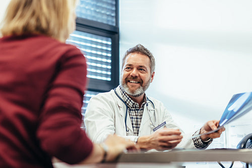Happy doctor talking with patient in his office