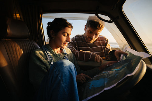 Couple plans road trip from a van at sunset