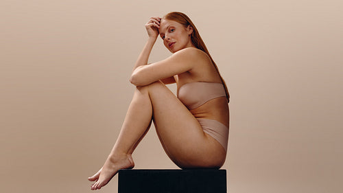 Wellness model seated in neutral studio pose showing skin