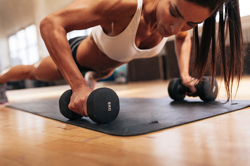 Muscular woman doing push-ups on dumbbells