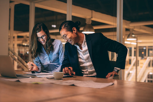 Cheerful business partners working late night in office
