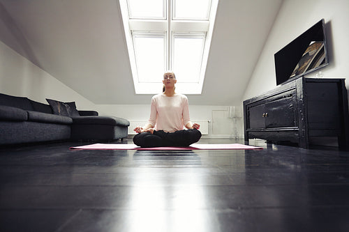 Healthy young woman meditating at home