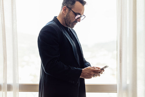 Businessman texting on mobile phone in hotel room