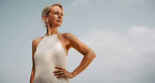 Confident woman in a white dress outdoors under a clear sky