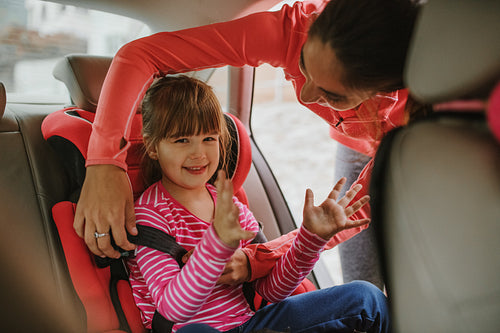 Woman buckling up on child in car safety seat
