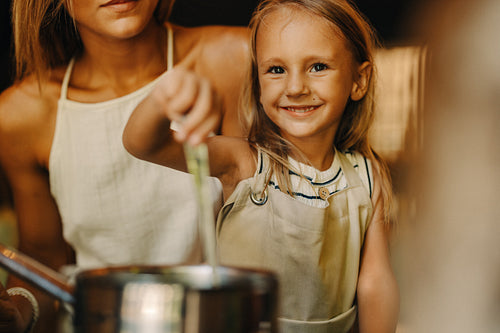 Smiling child cooking with parent in a cozy kitchen