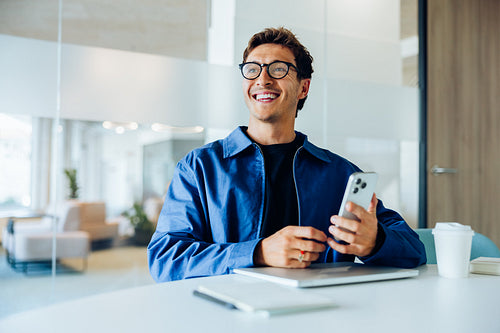 Happy tech worker uses phone in office