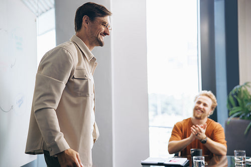 Business man getting applauded for his successful work on a team project
