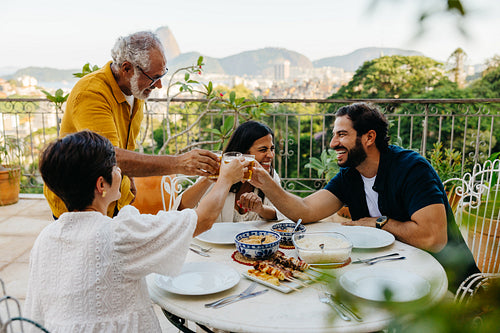 Family enjoying a barbecue meal on a terrace with a scenic view