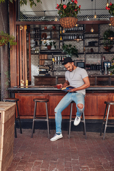 Handsome young man having coffee and reading book