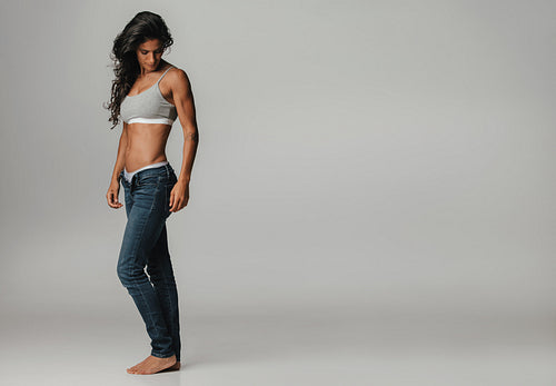Beautiful tanned woman with unbuttoned jeans