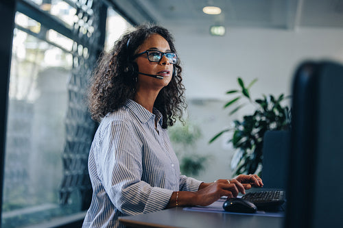 Businesswoman with headset working on computer