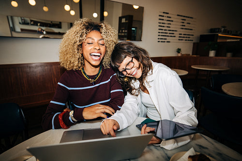 Friends sharing laughter while working on laptop