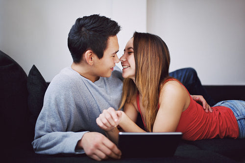 Romantic teenage couple on couch with digital tablet