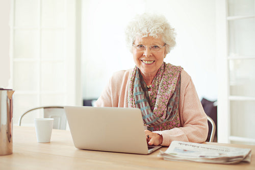 Cheerful Senior Woman at Home with Laptop