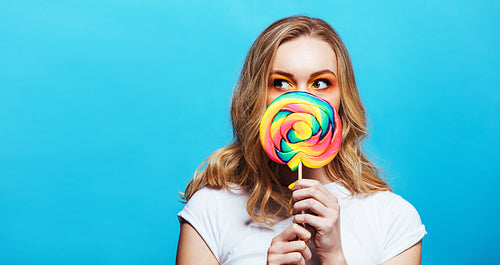 Young woman holding lollipop in front of her mouth