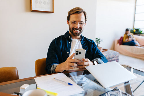 Businessman smiles while using smartphone at desk