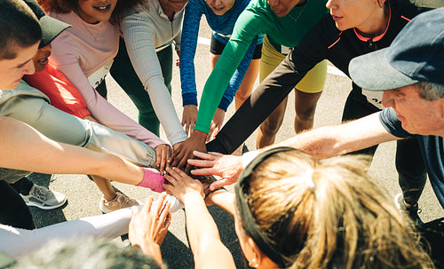 Group of runners uniting in a team huddle before marathon