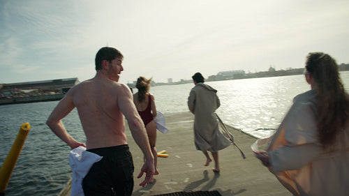 Swimming friends jump from dock for cold plunge in urban open water