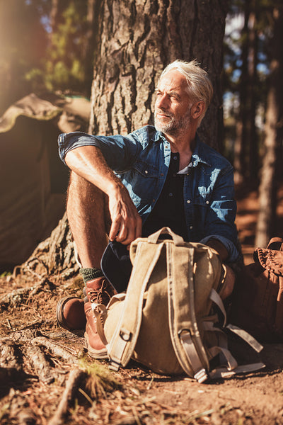 Senior man sitting by a tree and looking away