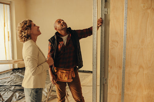 Happy female homeowner discussing interior remodeling plans with a construction worker in a house