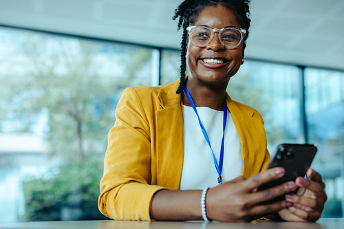 Confident businesswoman smiling while texting in modern office