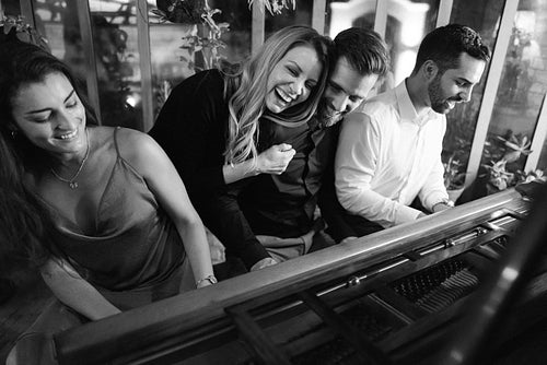 Group of friends playing the piano together