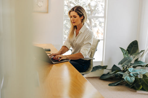 Modern businesswoman typing on a laptop in her office