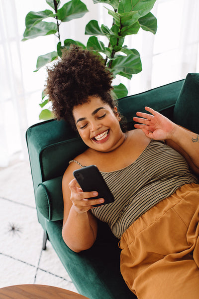 Woman relaxing on couch with cell phone at home