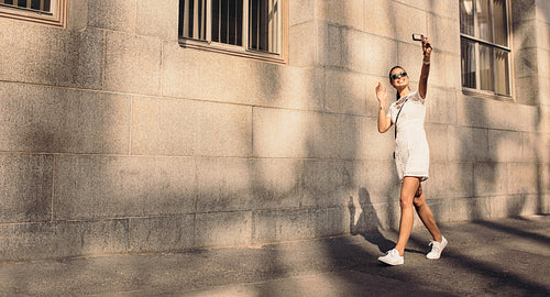 Young tourist taking a selfie walking in the street.