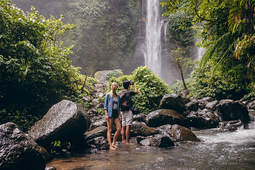 Young couple standing by the stream near the waterfall