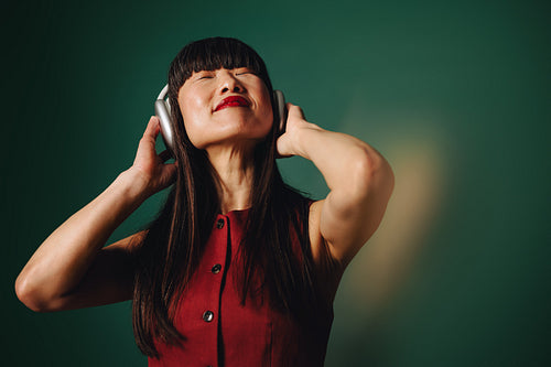 Sound surrounds the woman as she listens with headphones in the studio