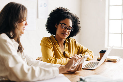 Fashion designers using a smartphone while having a discussion in an office