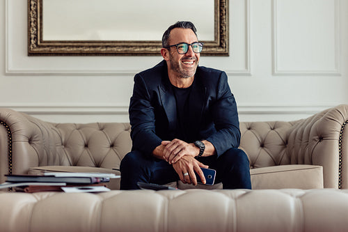 Happy mature businessman sitting in hotel room
