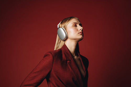 Woman in suit wearing headphones in red studio portrait