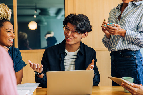 Young professionals smiling and discussing ideas in a modern office setting