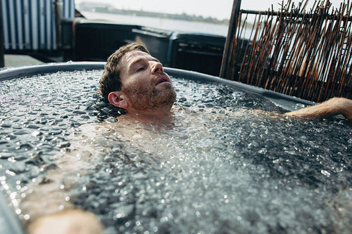 A wellness-minded man sits in ice water for recovery and cold therapy.