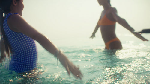 Mother and daughter enjoying a luxurious tropical beach vacation, playing happily in the ocean water