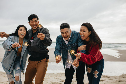 Asian friends enjoying with sparklers at the beach