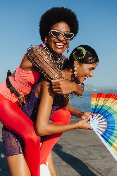 Friends celebrate carnival with rainbow fan and bright outfits