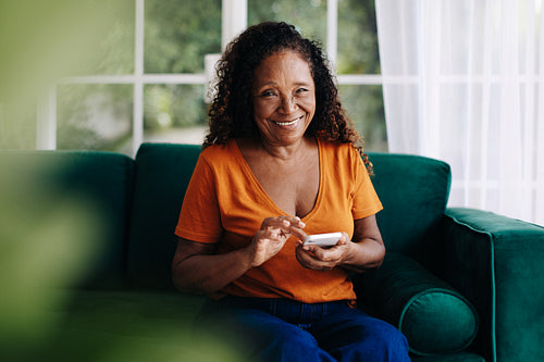 Happy retired woman using her smartphone to connect with other seniors online