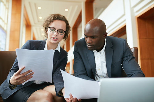 Two business partners sitting in cafe and discussing contract.