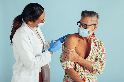 Doctor giving corona virus vaccine to mature man