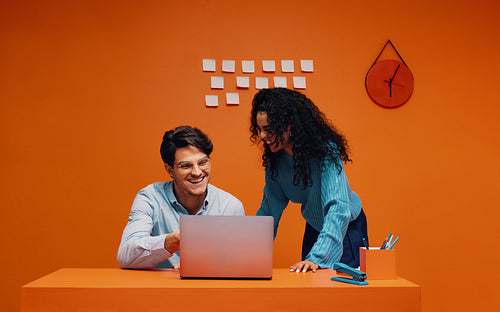 Colorful office scene with two business people discussing over a laptop in a vibrant setting