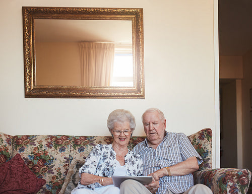Loving senior couple using digital tablet at home