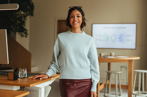 Woman smiling in office beside a desk for a business portrait