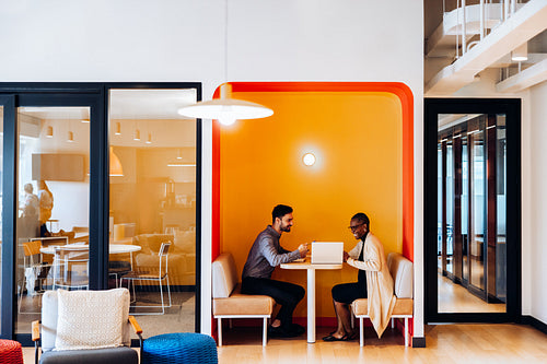 Two people discussing work in a vibrant office seating area