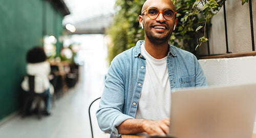 Happy business man sitting in a cafe, working with his laptop