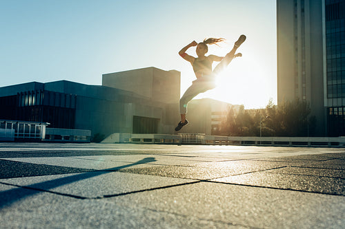 Woman practicing roundhouse kick outdoors