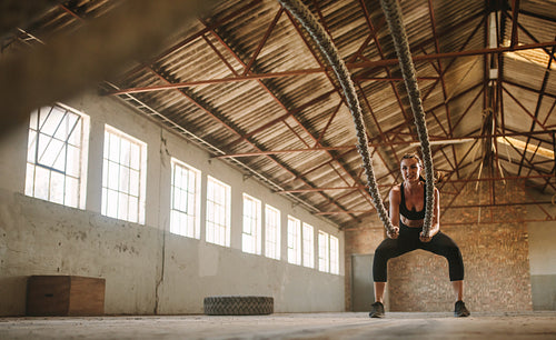Woman exercising battling ropes at cross training gym